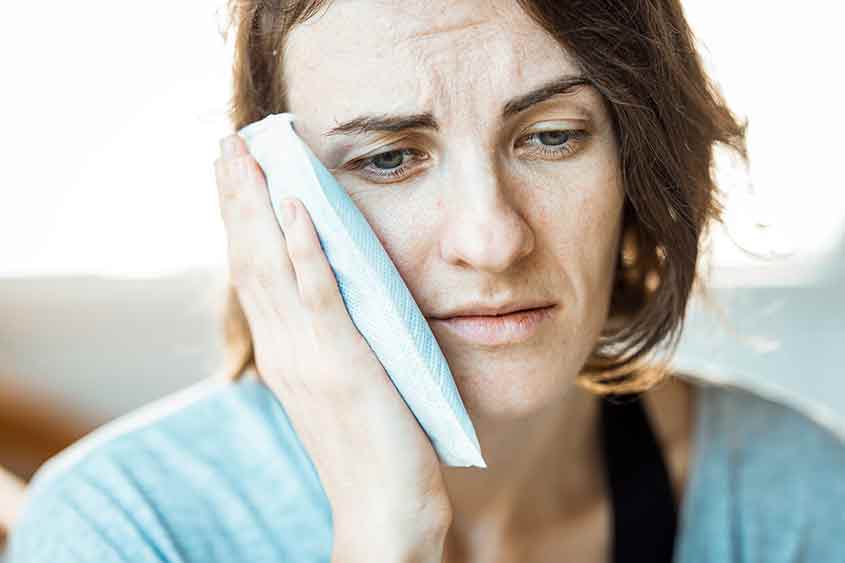 Woman holding the side of her face in pain.