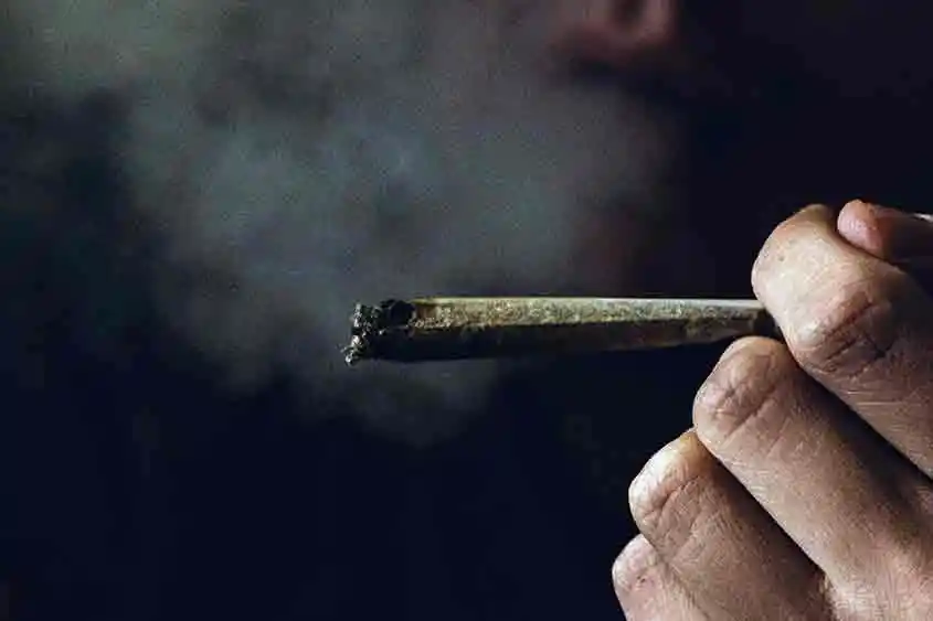 Closeup of a hand holding a joint, and smoke