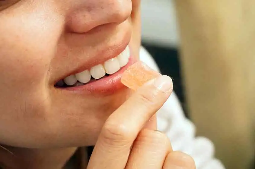 Closeup of a woman eating a cannabis edible gummy in her mouth