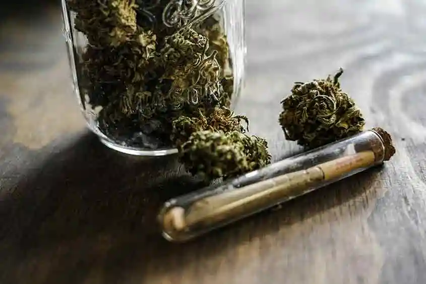 A marijuana blunt beside a jar of cannabis flower