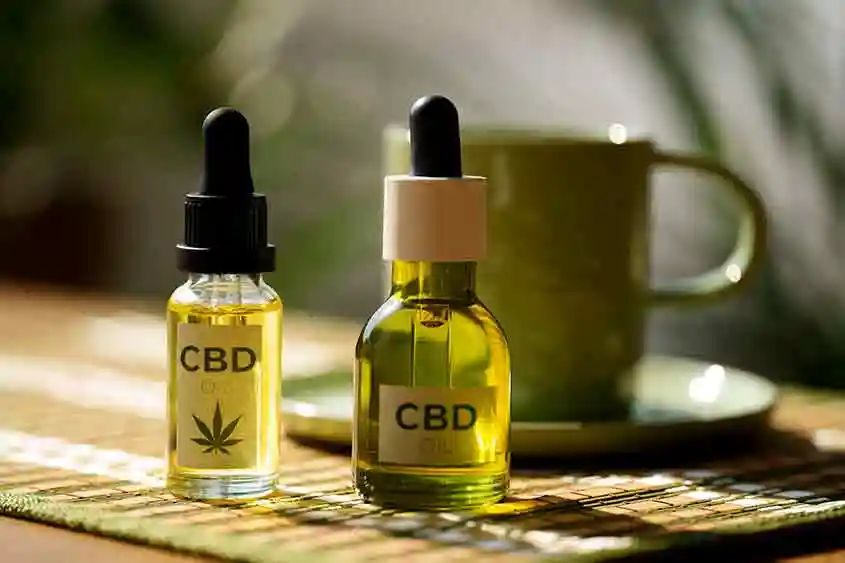 CBD oil tinctures lying on a table with a cup.