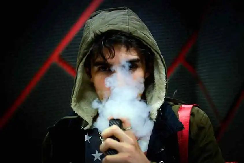 Man in hoodie using a vaporizer