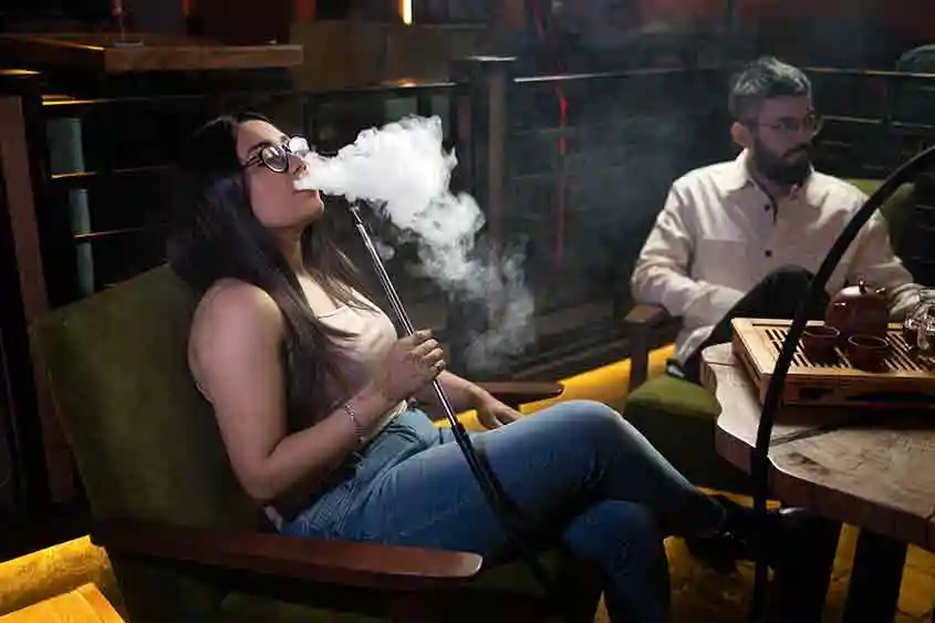 A lady enjoying vaping from a hookah. Recreational feel.