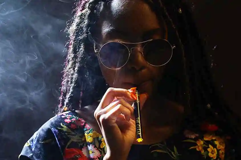 African American woman using a vape pen.