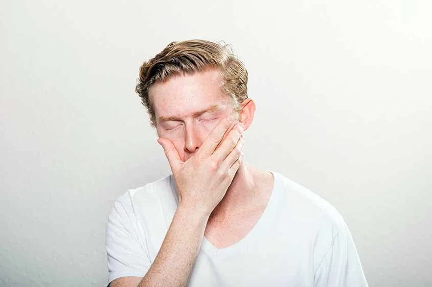 Man holding his mouth possibly feeling nausea. Medical marijuana can help relieve such conditions!